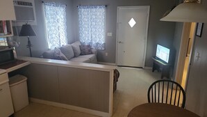 A compact living space with a sofa, a television, a lamp, and a dining area. - Clean, full kitchen, stand alone cabin adjoining Lake Barkley State Park (Cadiz)