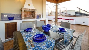 An outdoor dining area with a brick oven, wicker chairs, and a tiled tablecloth. - Duke of Aosta Terrace with private mini-pool (Acquedolci)