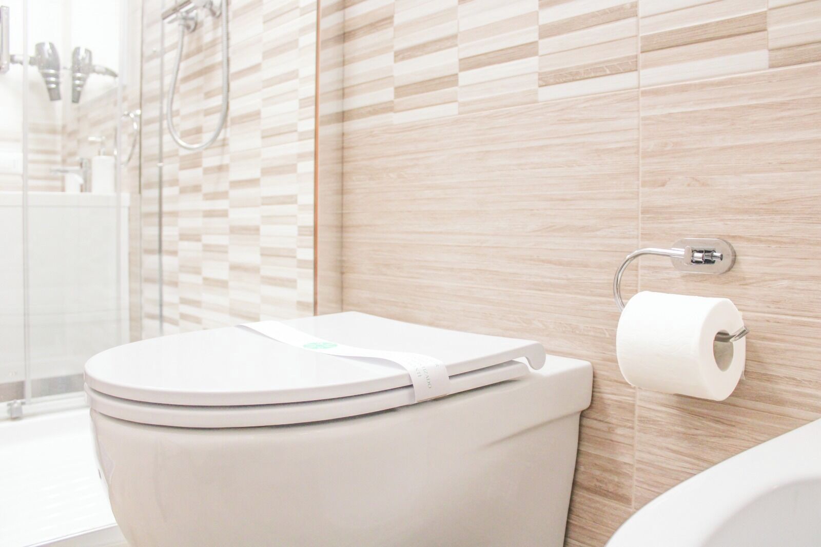 Une salle de bain moderne équipée de toilettes, d’une douche et d’un porte-rouleau de papier toilette fixé au mur.