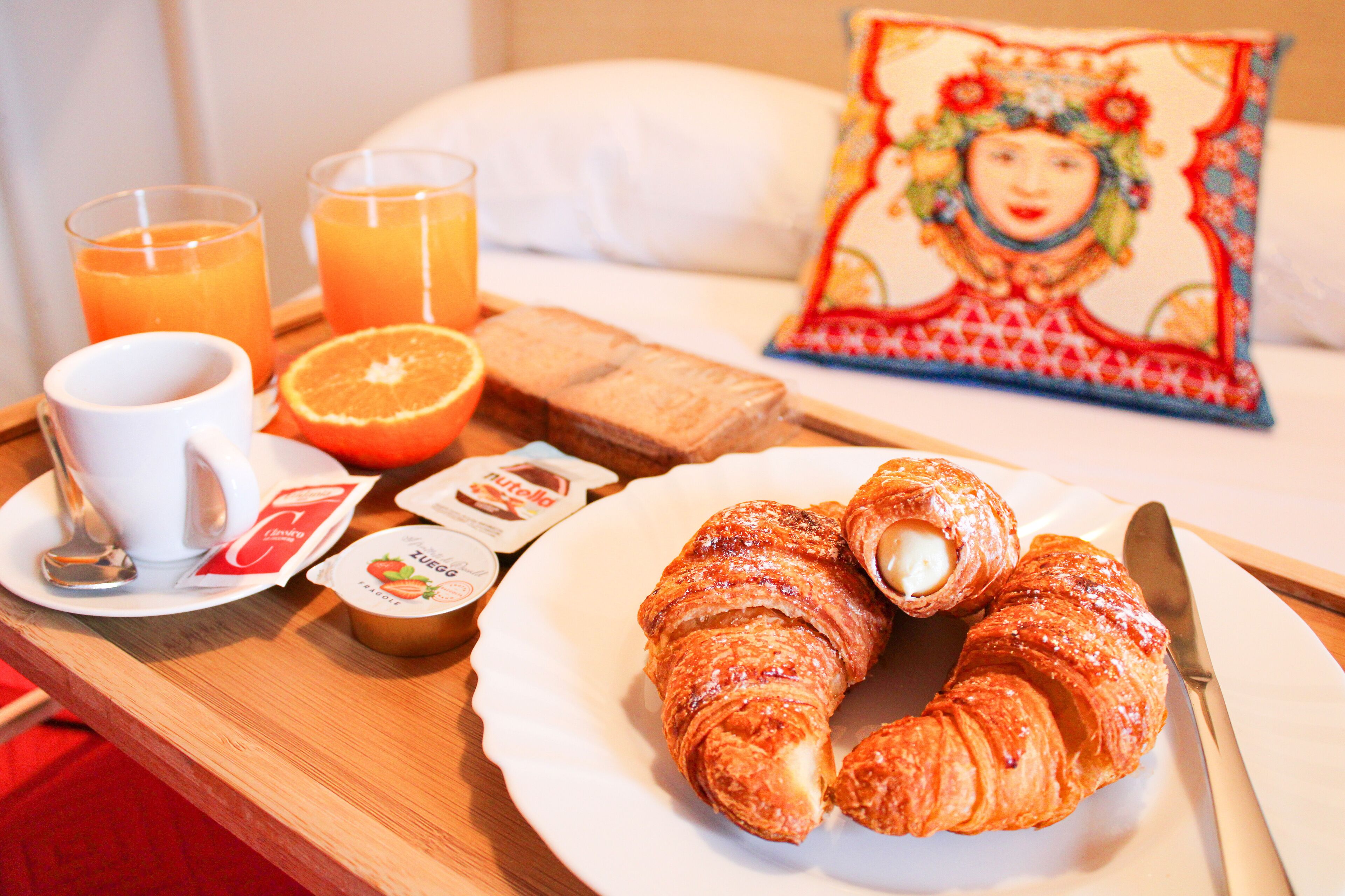 A breakfast tray with croissants, orange juice, and a cup of coffee.