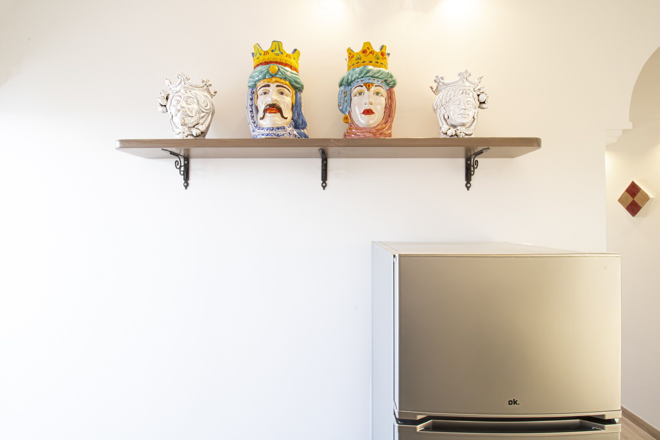 Eine Küche mit einem weißen Kühlschrank und einem Regal mit drei Keramikfiguren.