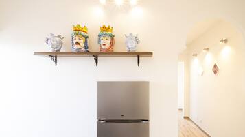 Eine Küche mit einem modernen Kühlschrank, einem Regal mit Dekoration und einem Flur mit Beleuchtung.