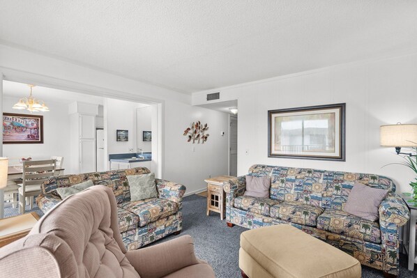 A living room with patterned sofas, a dining area, and a kitchen visible through an open doorway. - A532 at the Myrtle Beach Resort (Myrtle Beach)