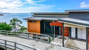 A modern building with a flat roof, large windows, and a covered outdoor area with a metal railing.