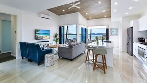 A modern living room with a sofa, a dining area, and a kitchen.