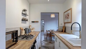 Una cucina moderna con piani in legno, un fornello a gas, un lavello e un'area pranzo con tavolo e sedie.