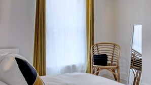 Una camera d'albergo con un letto, una sedia e una finestra con tende.
