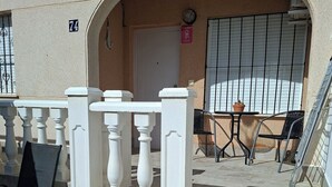 Un espace extérieur agrémenté d’une balustrade blanche, d’une sculpture en pot et d’une table avec des chaises.