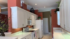 A kitchen with white cabinets, a stove, and a refrigerator.