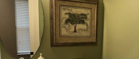 A bathroom with a pedestal sink, toilet, and framed artwork on the wall.