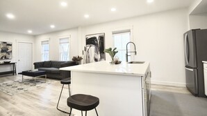 Une cuisine moderne avec un îlot central, un coin repas avec un canapé et un salon avec une table basse.