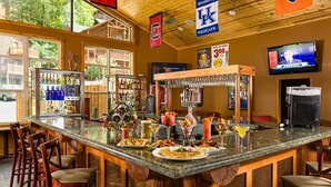 A bar area with a counter, stools, and a variety of drinks. - Celebrate July 4th in the beautiful Smoky mountains!! (Gatlinburg)