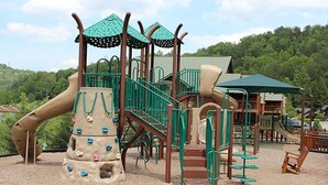 A playground with climbing structures, slides, and a wooden playhouse. - Celebrate July 4th in the beautiful Smoky mountains!! (Gatlinburg)