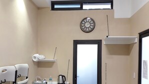 A small, compact room with a kitchenette, a clock on the wall, and a door leading to another room. - CIUDAD DE MEXICO UNAM GUEST HOUSE (Ciudad de México)