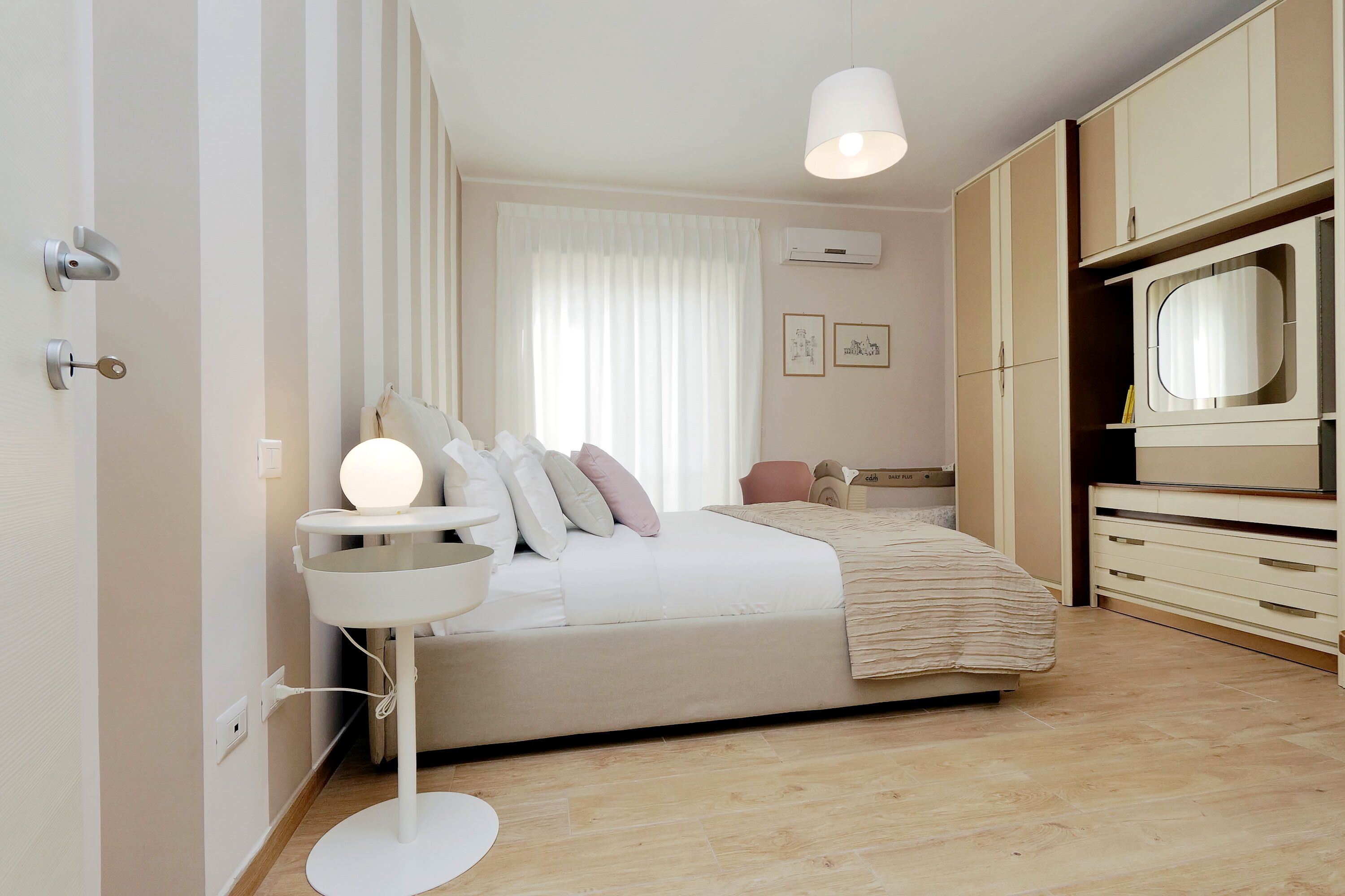 A modern bedroom with a bed, bedside table, and a mirror.