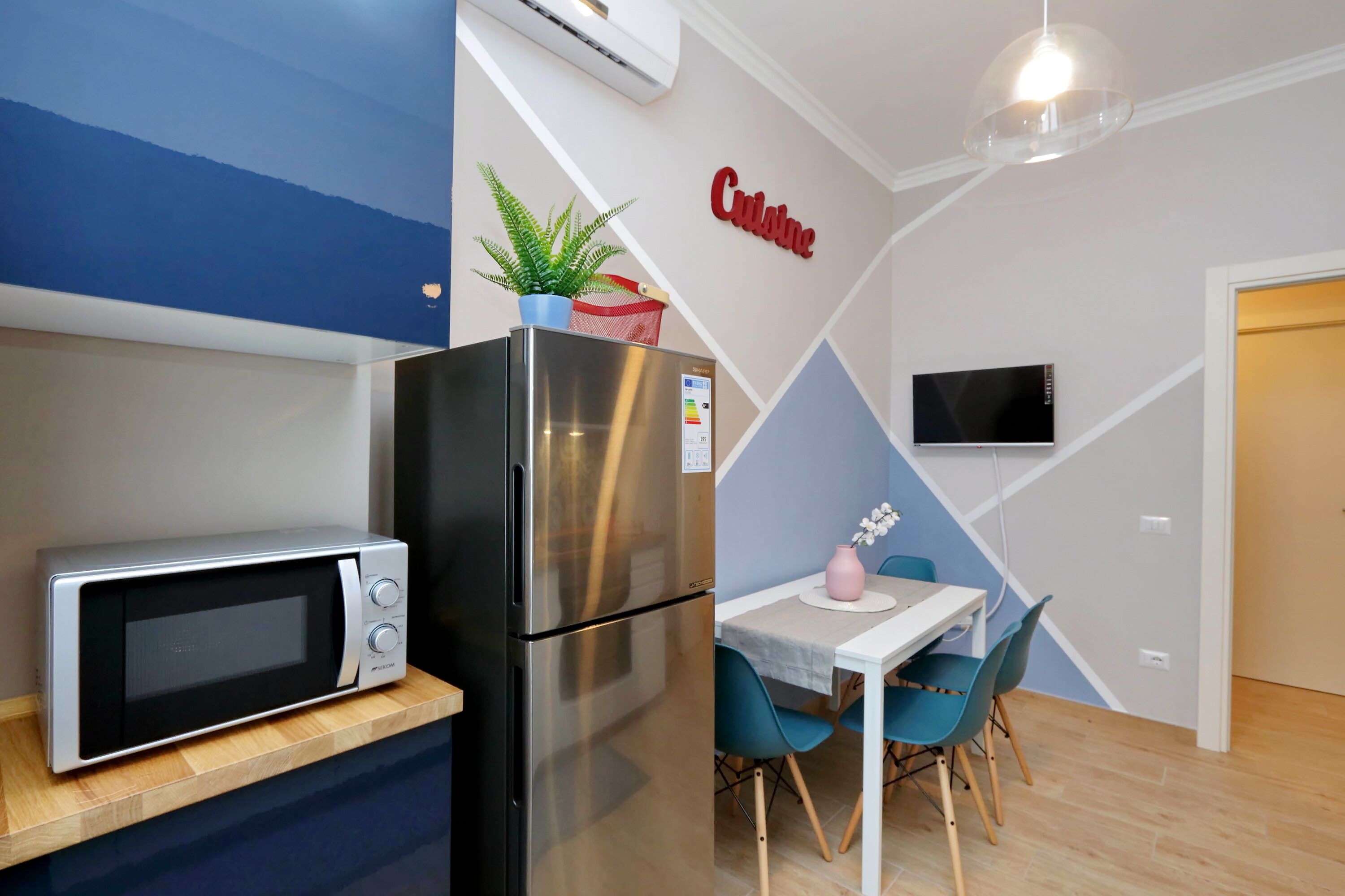 Una cocina compacta con microondas, refrigerador y comedor con mesa y sillas.