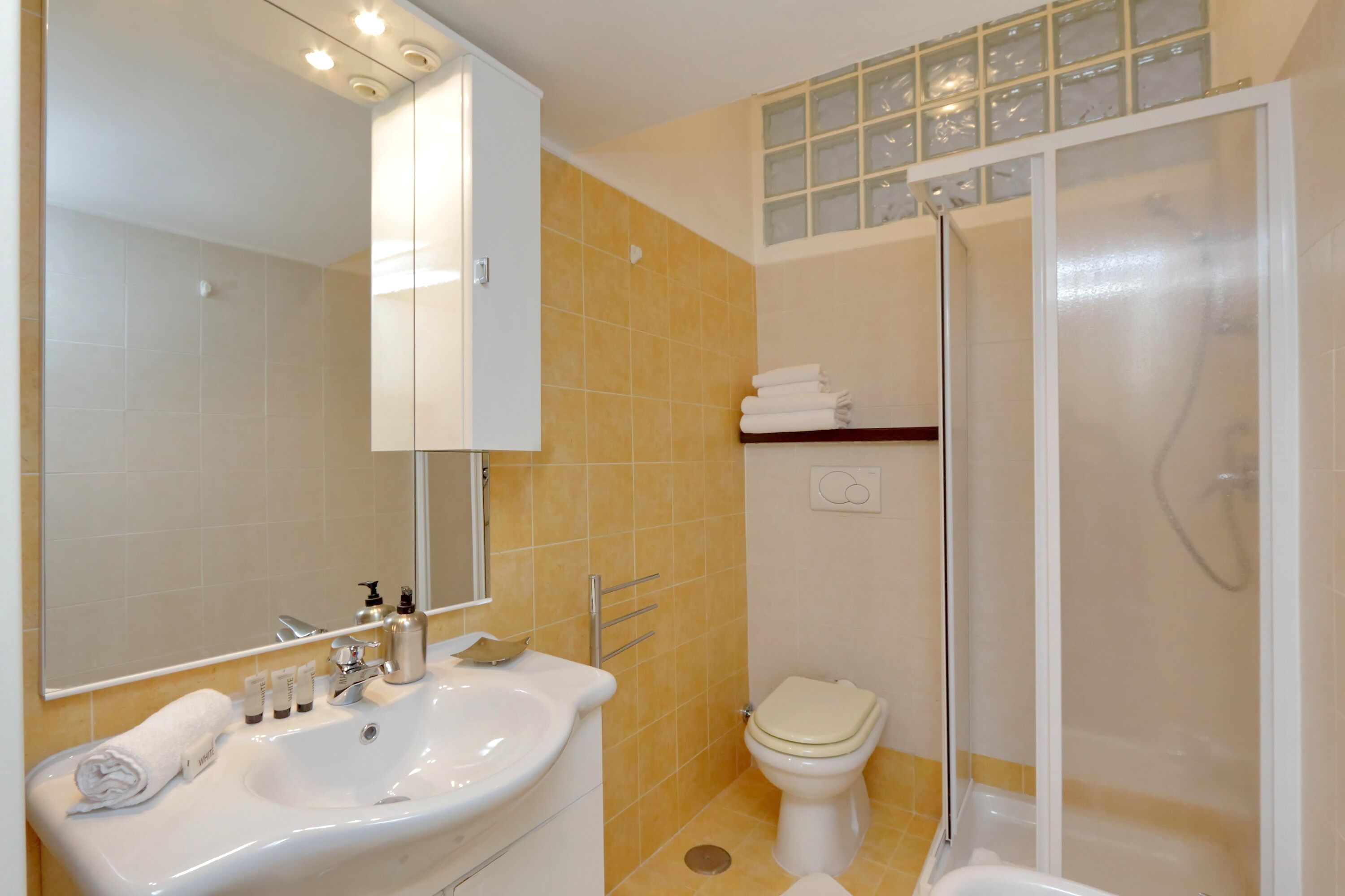 A bathroom with a sink, mirror, toilet, and shower.