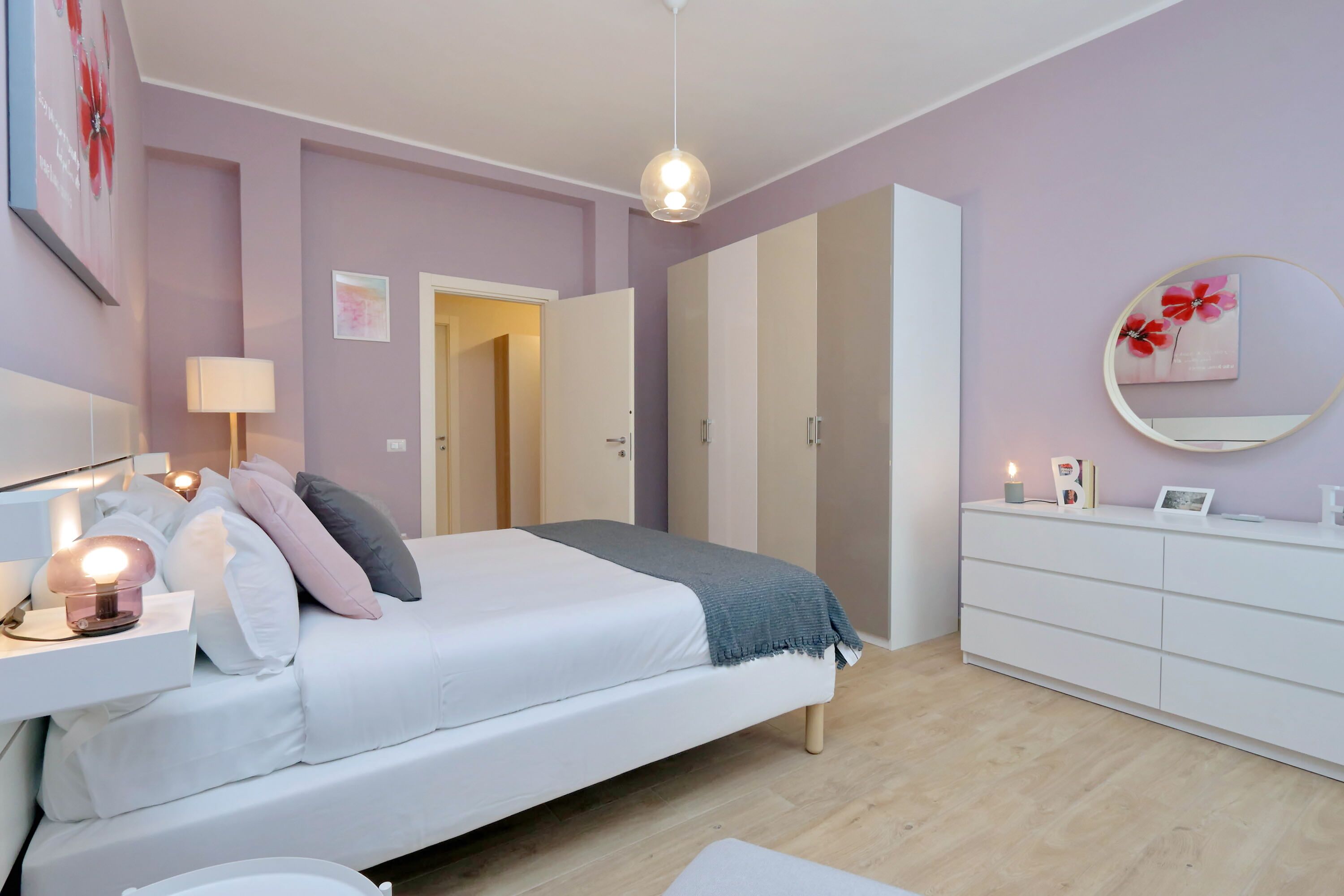 Une chambre à coucher comprenant un lit, une table de chevet, une lampe, une commode et un miroir au mur.