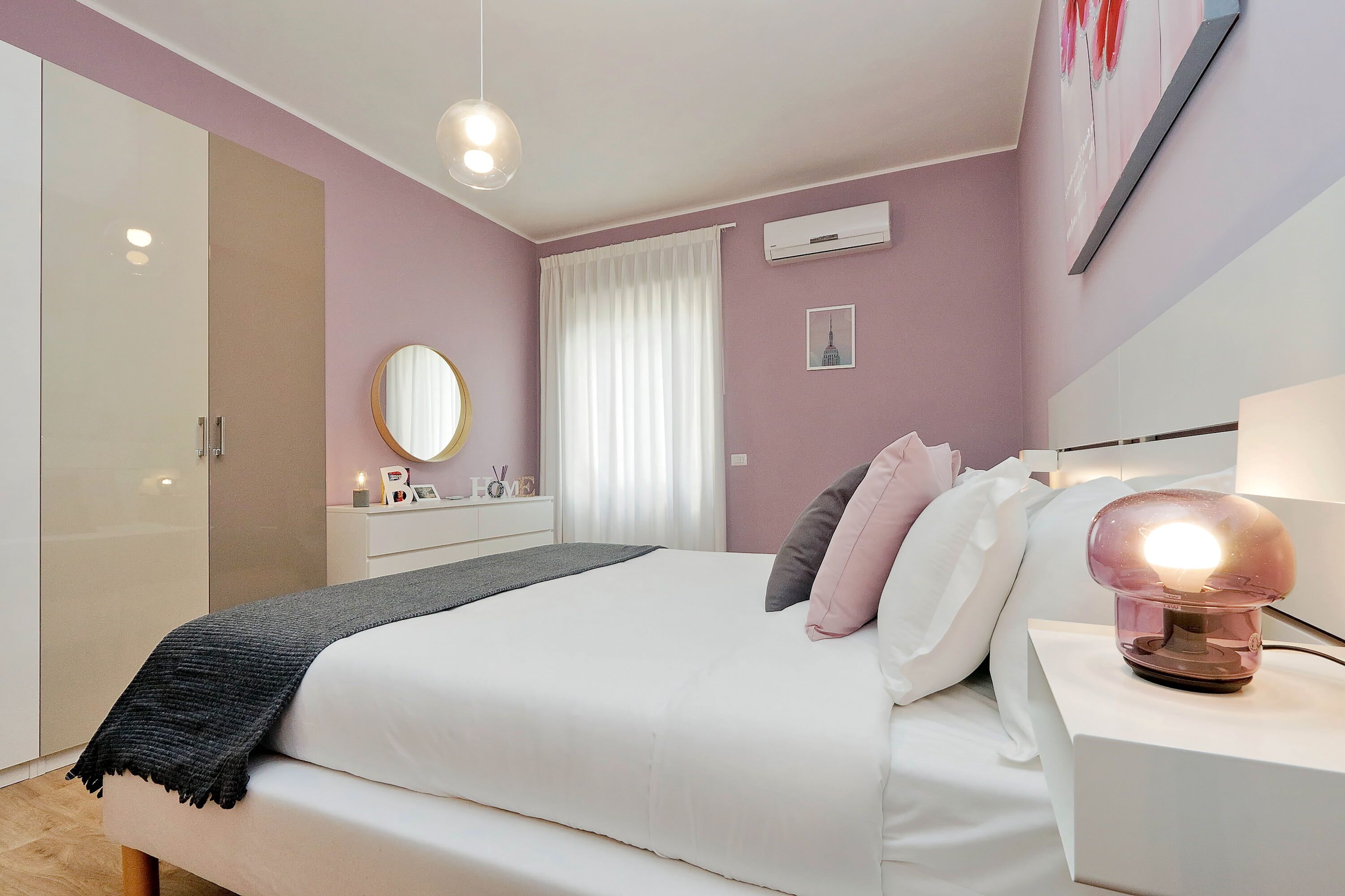 A neatly arranged bedroom with a bed, bedside table, and a wall-mounted lamp.