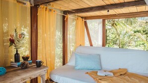 A cozy room with a bed, a wooden table with a vase, books, and a cup.