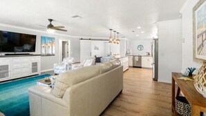 A spacious living area with a large sofa, a television, and a dining table with chairs. - Turquoise Turtle - pool and spa, beautifully furnished (Englewood)