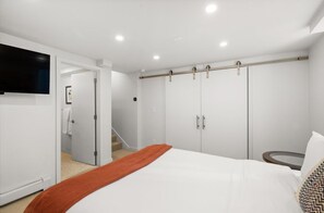 Ein Schlafzimmer mit einem Bett, einem an der Wand montierten Fernseher und einem Kleiderschrank mit Schiebetür.