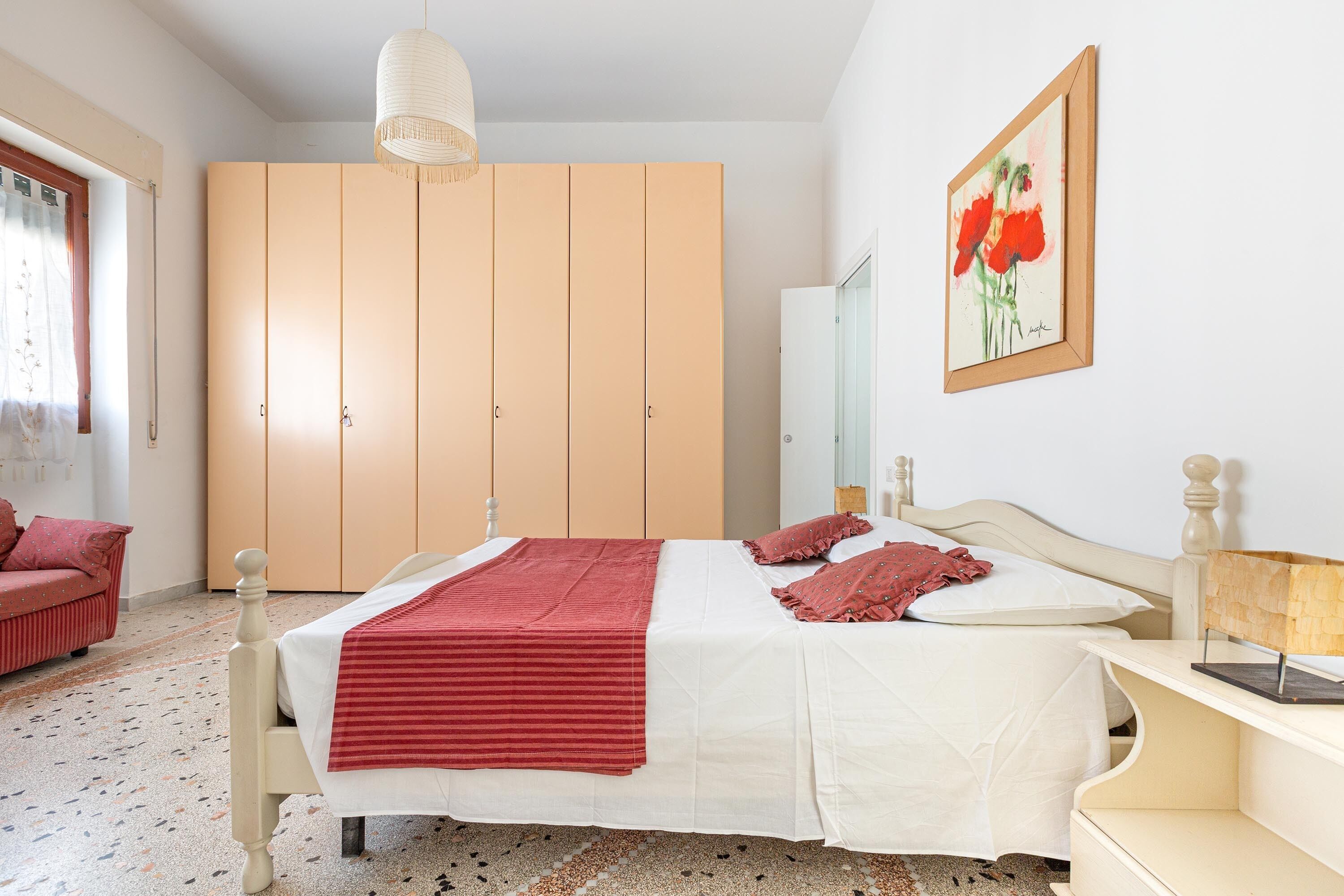 Una camera da letto con un letto, un armadio, un quadro e un comodino.