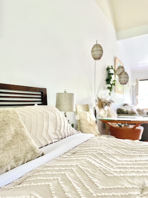 A bed with a wooden headboard, a white textured blanket, and a patterned throw. - Tropical, Bright Princeville Studio with Mountain Views (Princeville)