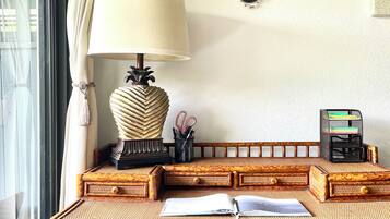 A rattan desk with a lamp, a plant, and a pen holder.