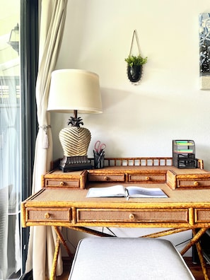 A rattan desk with a lamp, a plant, and a pen holder.