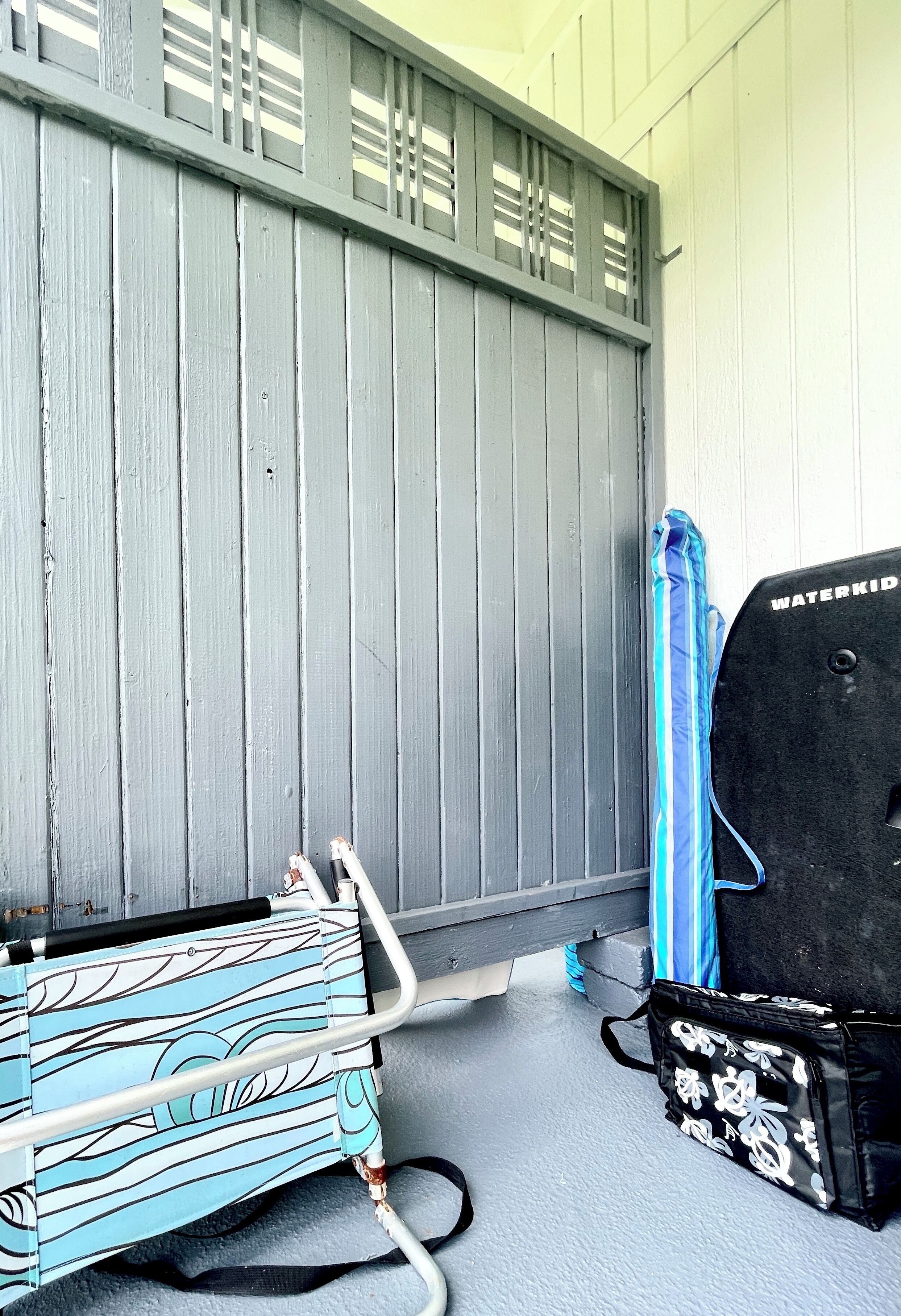 A room with a grey wooden wall, a blue towel, and a black water pump.