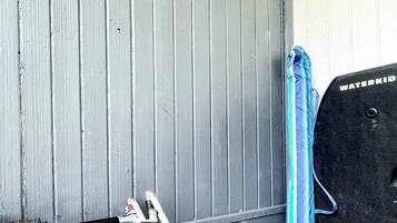 A room with a grey wooden wall, a blue towel, and a black water pump.