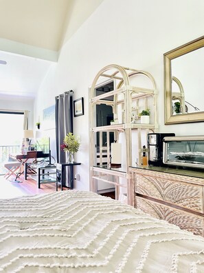 A hotel room with a bed, a television, a mirror, and a balcony with a view. - Tropical, Bright Princeville Studio with Mountain Views (Princeville)