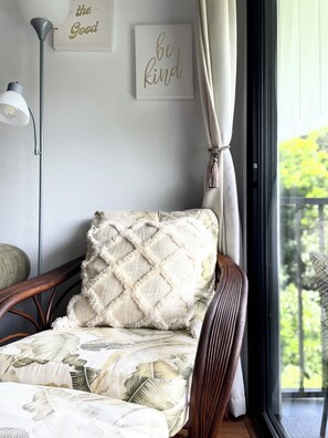 A room with a wooden chair, a cushion, a wall with motivational quotes, and a view of greenery outside. - Tropical, Bright Princeville Studio with Mountain Views (Princeville)