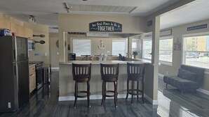 A modern kitchen with a central island, bar stools, and a ceiling fan. - BRAND NEW 16x14 Heated Swim Jacuzzi Sleeps 8 Beach Front! No Condo Park 4 Cars! (Fort Myers Beach)