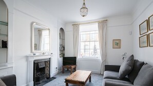 Una sala de estar con chimenea, televisor, sofá y candelabro.
