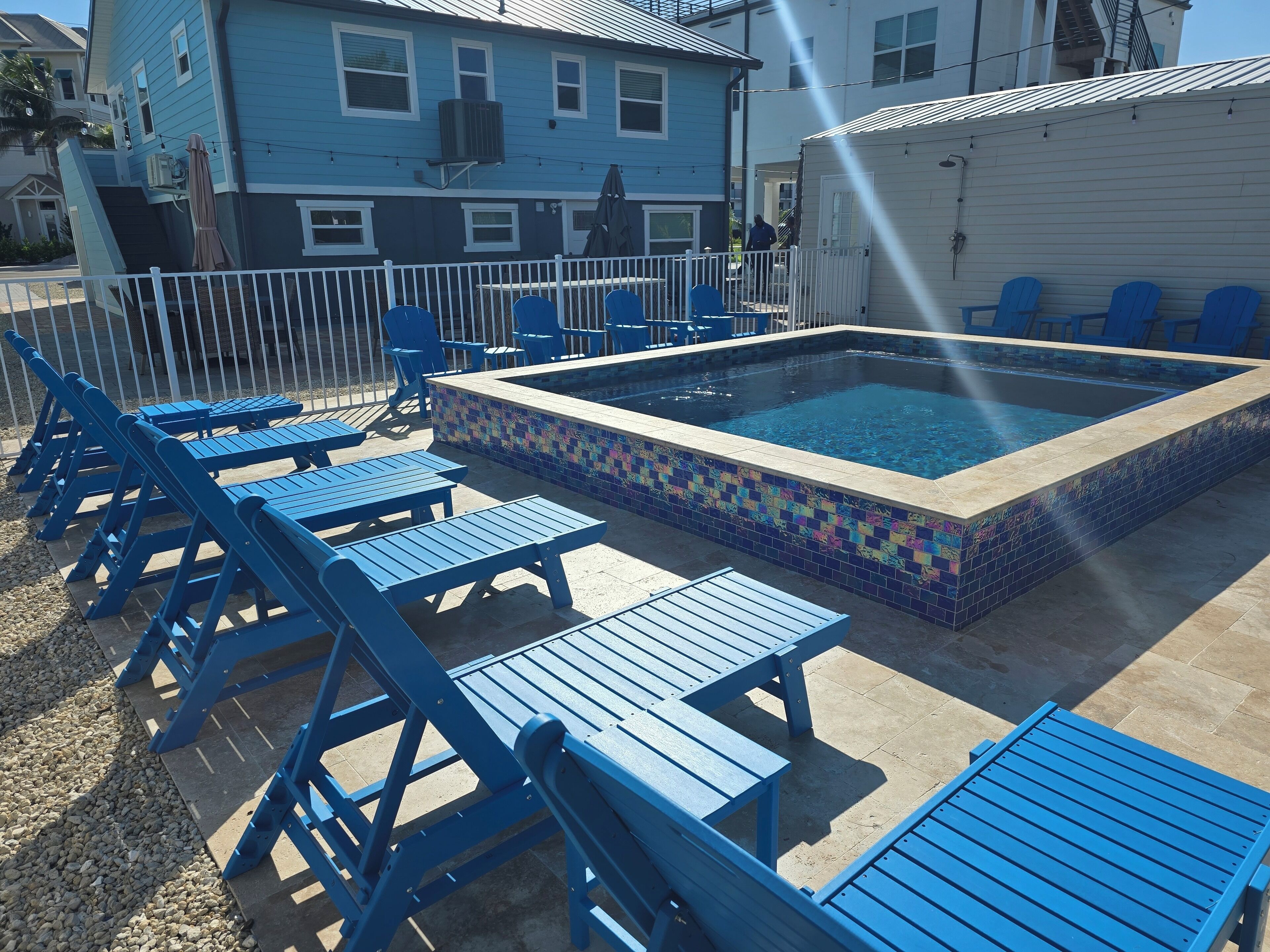 A pool area with blue lounge chairs and a tiled pool.