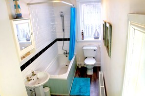 Bañera con ducha, toallas, jabón, papel higiénico