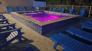 En swimmingpool med blå stole og en flisebelagt solterrasse.