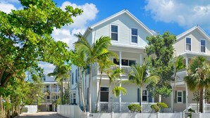 A two-story house with a balcony, surrounded by a white picket fence and palm trees. - Eisenhower Retreat (Key West)
