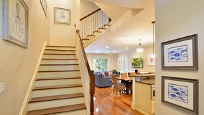 A spacious living area with a wooden staircase, a dining area, and a kitchen. - Eisenhower Retreat (Key West)