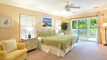A bedroom with a bed, a nightstand, a lamp, a window with blinds, a ceiling fan, and a view of the outdoors.