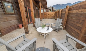 En terrasse med fire Adirondack-stole, et rundt bord og en potteplante.