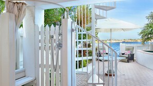 A white spiral staircase leading to a balcony with a pool view. - Island Chi c (Key West)