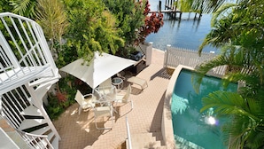 A rooftop pool area with a white fence, lounge chairs, and a grill. - Island Chi c (Key West)
