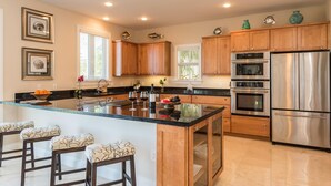 A modern kitchen with wooden cabinets, stainless steel appliances, a glass island, and bar stools. - 3 4 Tim e (Key West)