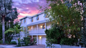A two-story house with a balcony, surrounded by lush greenery and a white picket fence. - 3 4 Tim e (Key West)