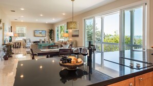 A spacious living area with a large glass table, a sofa, and a dining table set with wine glasses and a cheese board. - 3 4 Tim e (Key West)