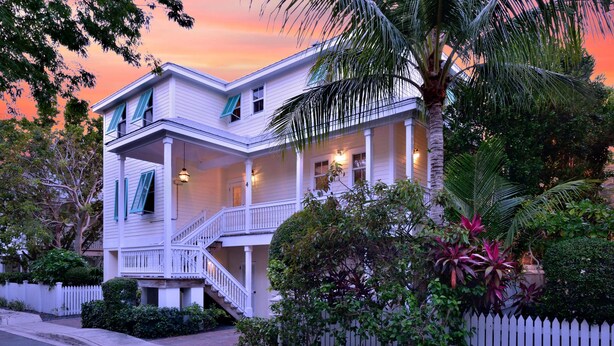 A two-story house with a porch, a staircase, and a white picket fence. - Banana Breez e (Key West)