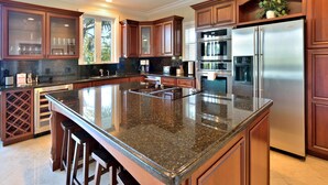A kitchen with granite countertops, stainless steel appliances, wooden cabinets, and a wine rack. - Southern Comfor t (Key West)